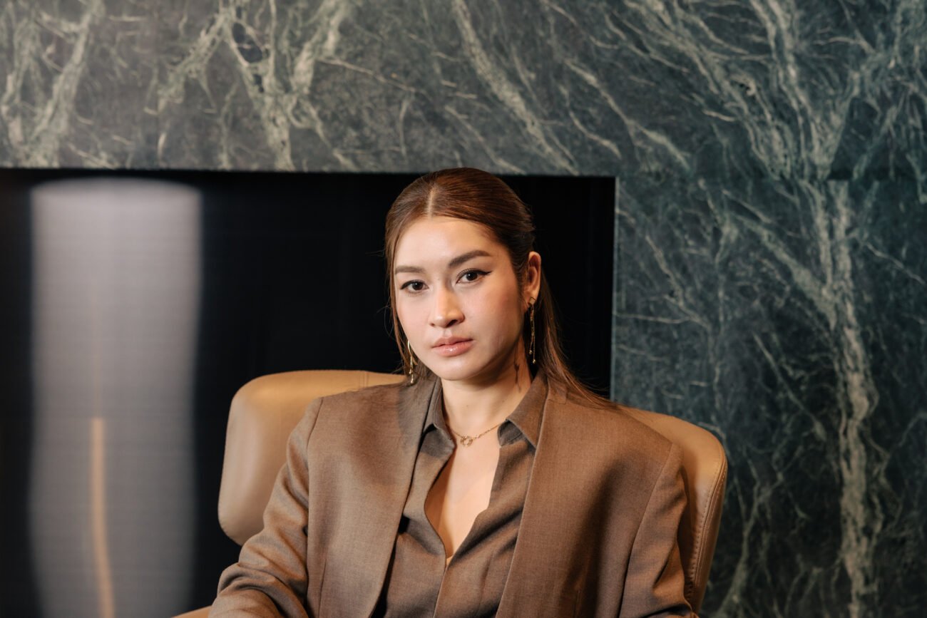 Give Warakorn seated in front of dark marble — portrait